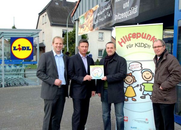 Foto: v.l.n.r. Steffen Pohlmann und Heinz Spies von der Lidl Vetriebs-GmbH erhalten von Projektkoordinator Marco de Luca und Landrat Manfred Müller das „Hilfepunkt“-Schild. 